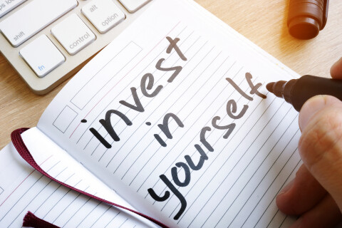Open geslagen schrift waarin met stift geschreven staat "Invest in yourself"